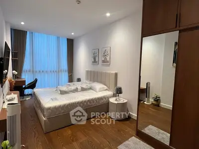 Spacious modern bedroom with elegant decor and large window for natural light.