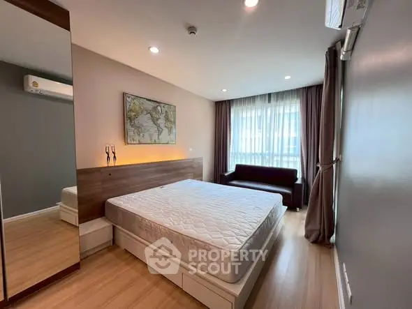 Spacious modern bedroom with large window and stylish decor in a contemporary apartment.