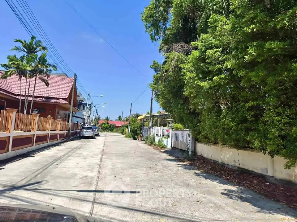 Charming residential street with lush greenery and cozy homes under a clear blue sky.