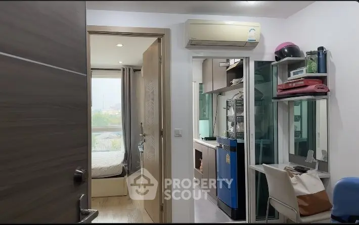 Compact apartment interior with bedroom and kitchen view, featuring modern appliances and air conditioning.