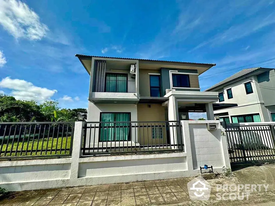 Modern two-story house with spacious yard and sleek design under clear blue sky.