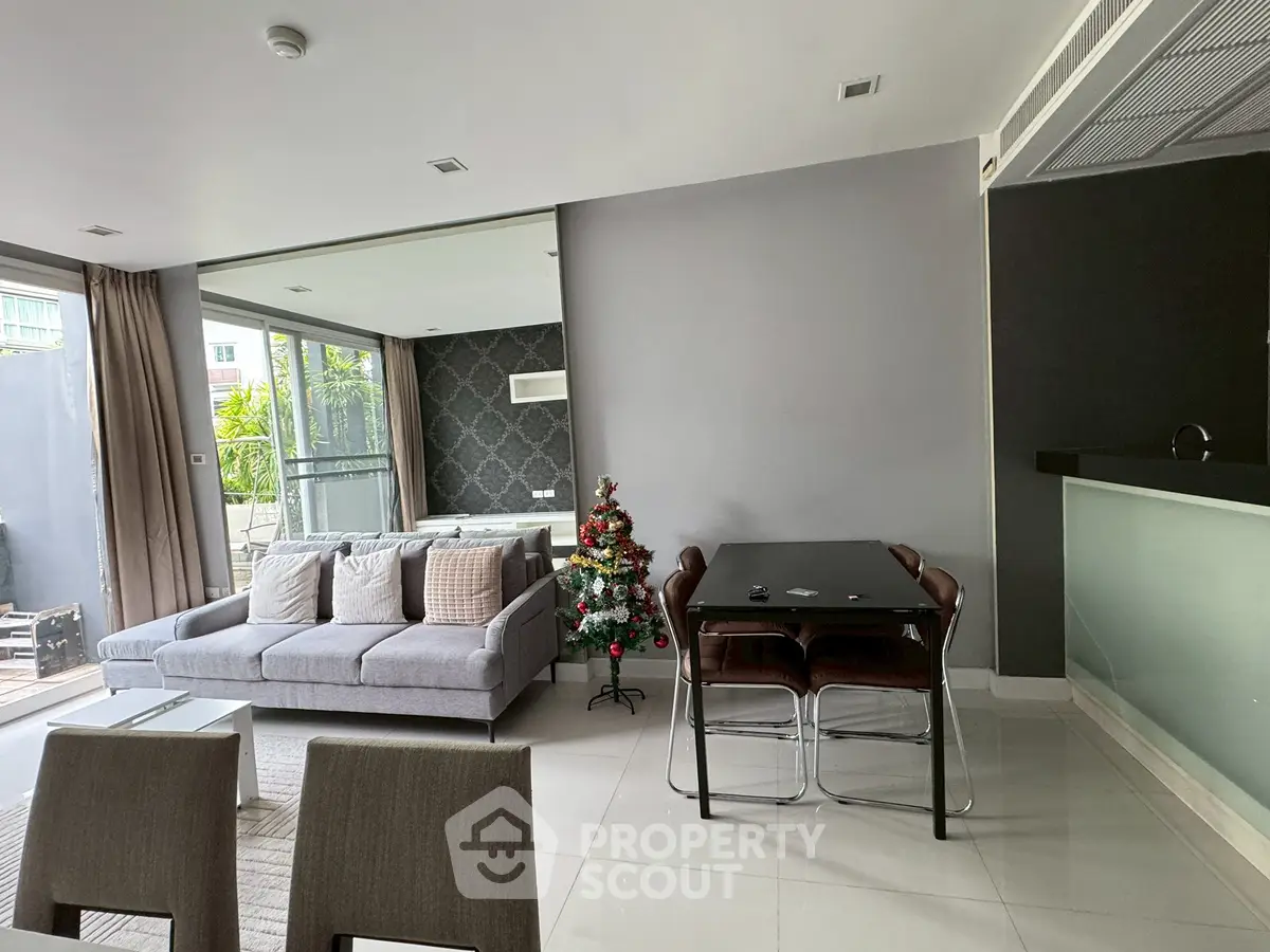 Modern living room with stylish decor and natural light, featuring a cozy sofa and dining area.