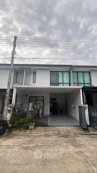 Modern townhouse exterior with gated driveway and plants