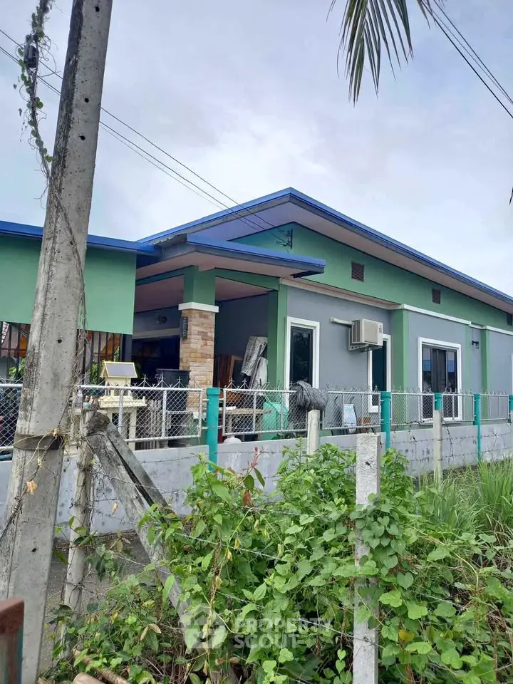 Charming single-story home with blue roof and lush greenery, perfect for serene living.