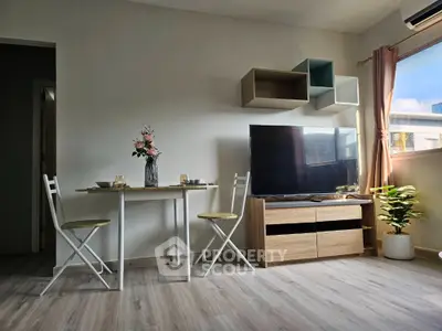 Modern living room with stylish decor, TV setup, and dining area in bright apartment.