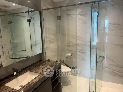 Luxurious modern bathroom with marble walls and glass shower enclosure