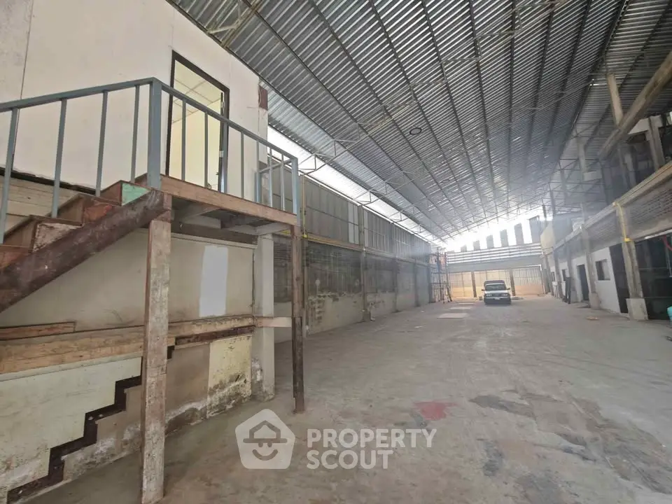 Spacious industrial warehouse with high ceilings and ample natural light, ideal for storage or manufacturing.