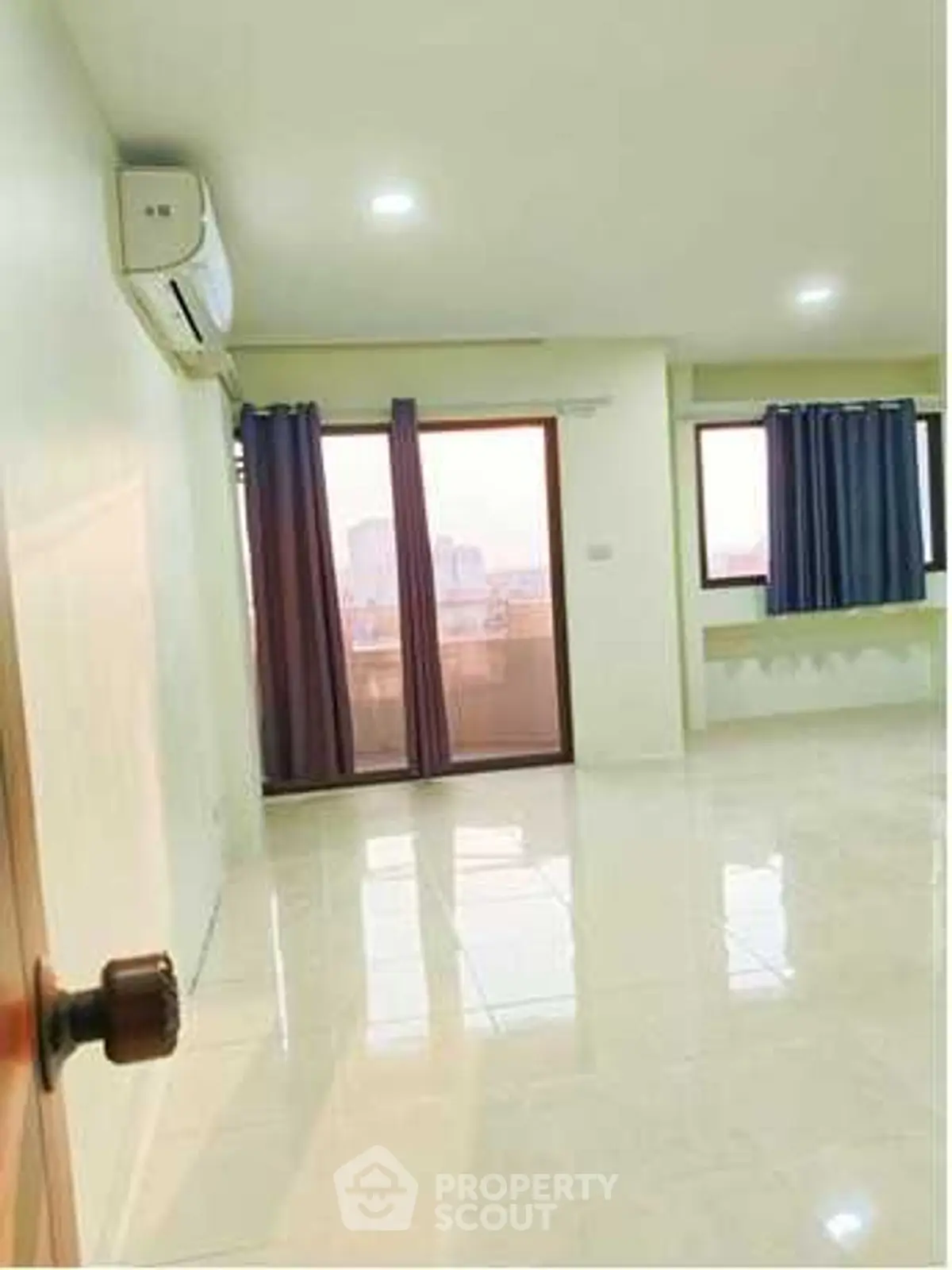 Spacious living room with large windows and city view, perfect for modern living.