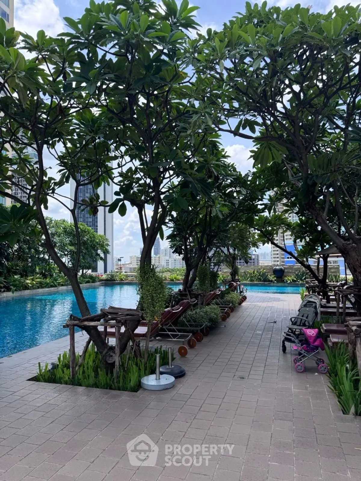 Luxurious urban poolside oasis with lush greenery and city skyline views.