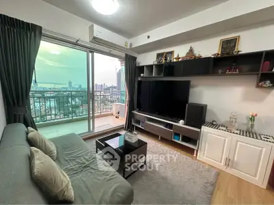 Modern living room with balcony and city view, featuring sleek furniture and entertainment setup.