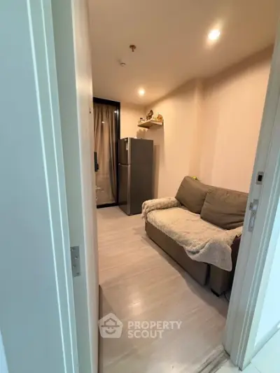 Cozy small living room with sofa and fridge, perfect for compact urban living.