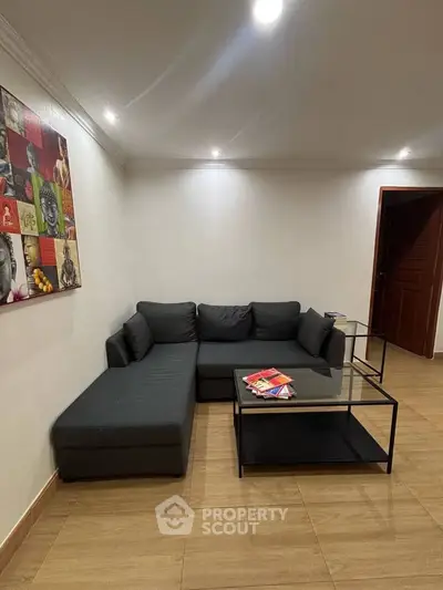 Modern living room with stylish black sectional sofa and glass coffee table, perfect for relaxation and entertaining.