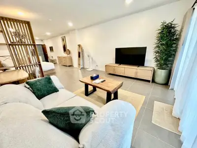 Spacious modern living room with stylish decor and large TV, perfect for relaxation and entertainment.