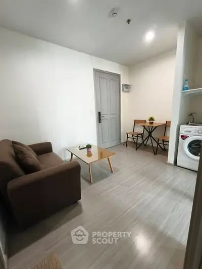 Cozy living room with compact dining area and washing machine in modern apartment.