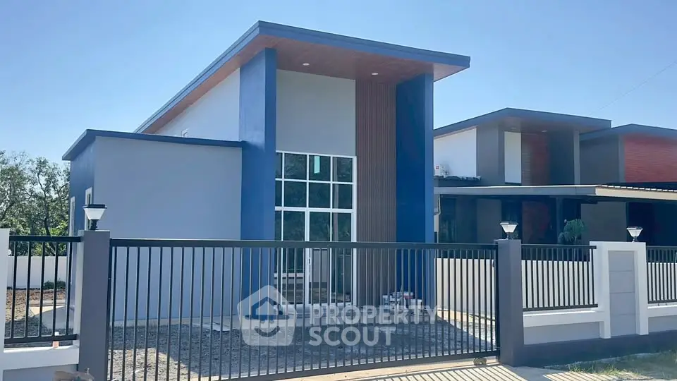 Modern minimalist house exterior with sleek design and large windows, featuring a stylish fence and clean lines.