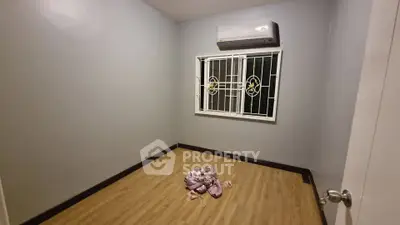 Minimalist empty room with wooden flooring and air conditioning unit