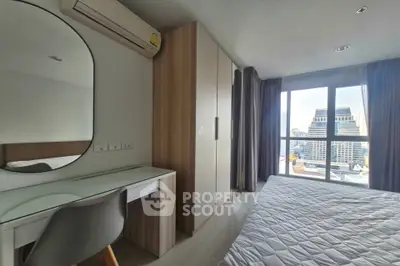 Modern bedroom with city view, featuring a stylish desk and large window.