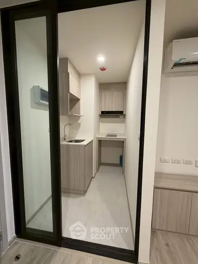 Modern compact kitchen with sleek cabinetry and built-in appliances in a stylish apartment.