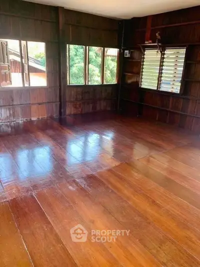 Spacious wooden interior with large windows offering natural light and scenic views, perfect for a cozy living space.
