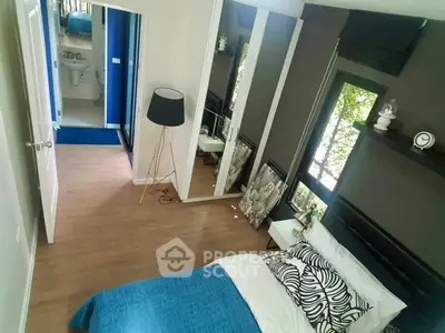 Modern bedroom with stylish decor and large mirror reflecting natural light