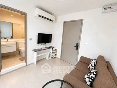 Modern living room with air conditioning and open view to bathroom, featuring a cozy sofa and wall-mounted TV.
