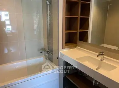 Modern bathroom with sleek sink and bathtub, featuring elegant shelving and contemporary design.