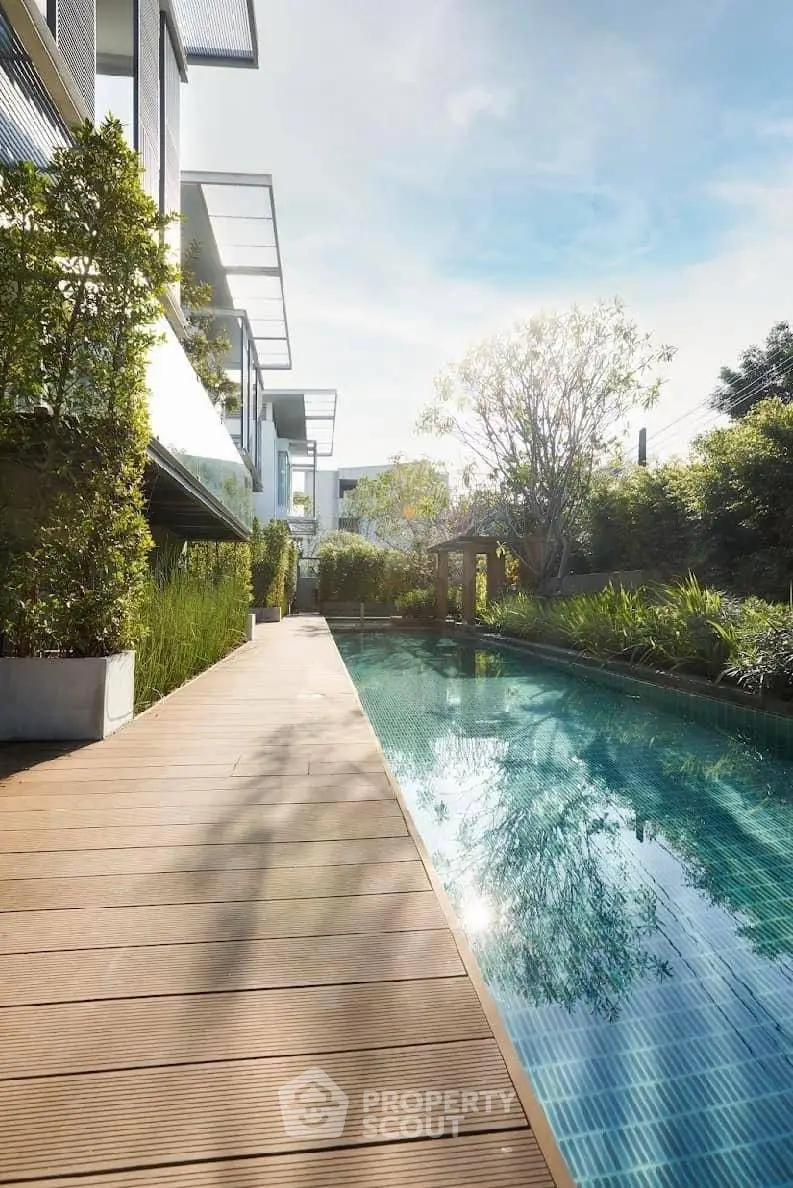 Luxurious modern poolside view with lush greenery and sleek architecture, perfect for relaxation and leisure.