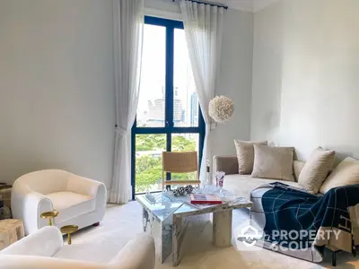 Elegant living room with plush seating, chic marble coffee table, and floor-to-ceiling windows offering a cityscape view, bathed in natural light.