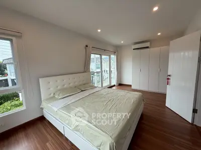 Spacious bedroom with large windows and modern furnishings in a stylish home.