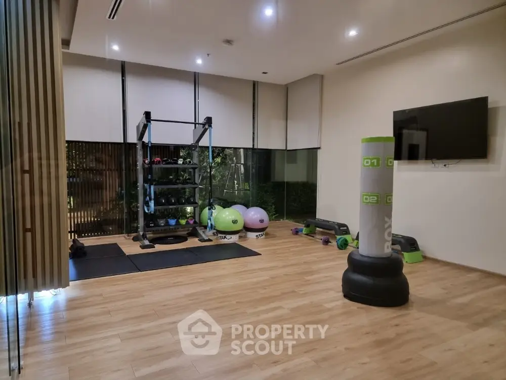 Modern gym with fitness equipment and wooden flooring in a residential building.