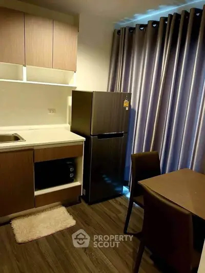 Cozy kitchen with modern appliances and dining area, featuring sleek cabinetry and elegant curtains.