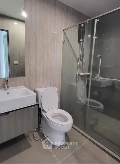 Modern bathroom with sleek design, featuring a glass shower enclosure and contemporary fixtures.
