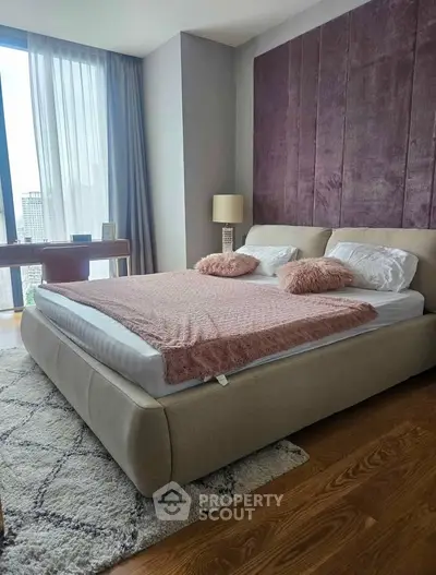 Luxurious bedroom with plush bed, elegant decor, and city view through large window.