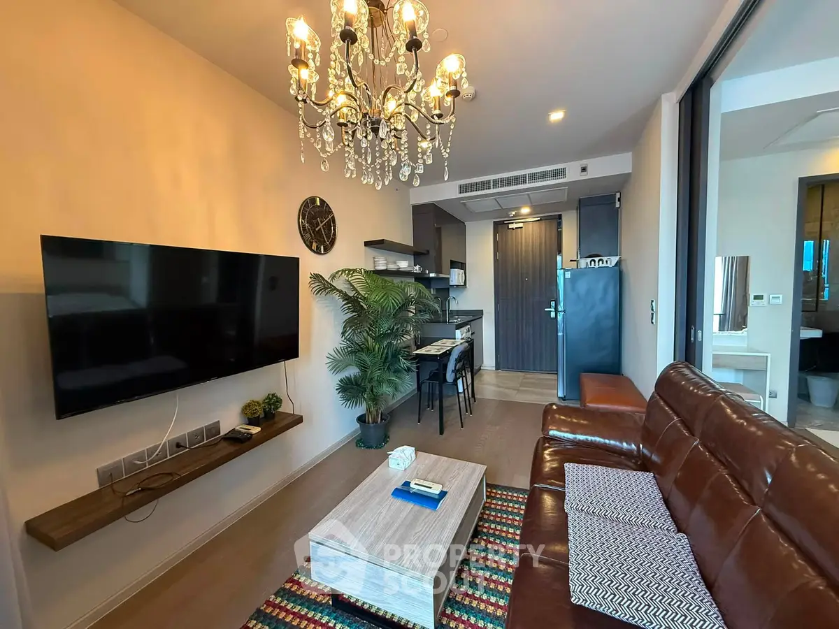 Stylish living room with leather sofa, chandelier, and modern decor in a contemporary apartment.