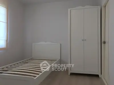 Minimalist bedroom with white bed frame and wardrobe, perfect for cozy living.