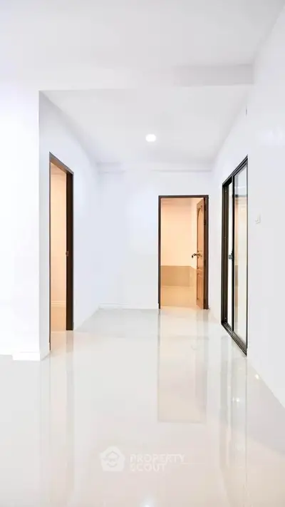 Spacious modern hallway with glossy floors and multiple doorways in a minimalist apartment.