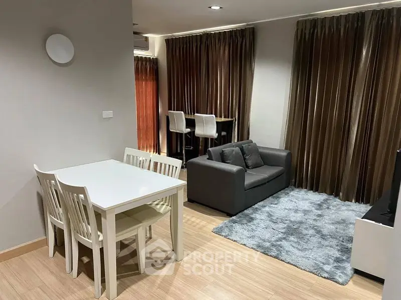 Modern living room with cozy seating and dining area, featuring elegant curtains and wooden flooring.