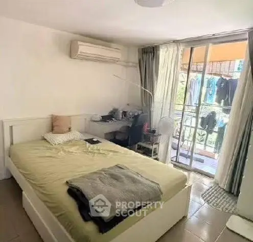 Cozy bedroom with balcony access, featuring a comfortable bed and workspace, ideal for urban living.