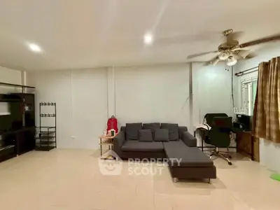 Spacious living room with modern furniture and ceiling fan, ideal for comfortable living.