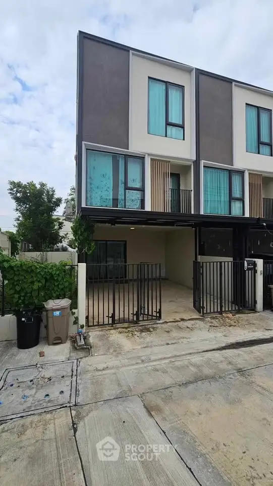 Modern three-story townhouse with gated parking and contemporary design.