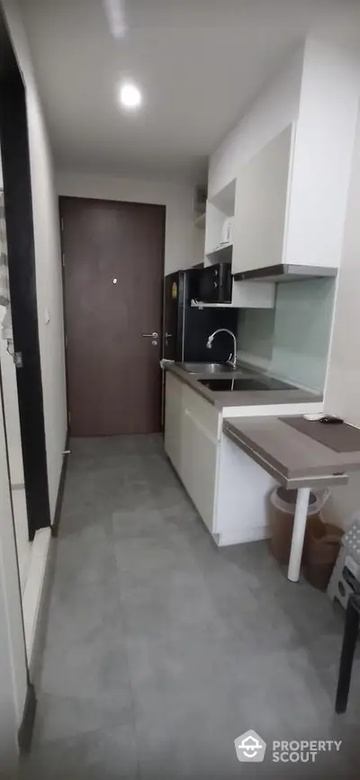 Modern compact kitchen with sleek cabinetry and integrated appliances in a contemporary apartment.