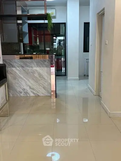Modern kitchen with sleek marble island and glossy tiled flooring in a stylish home interior.