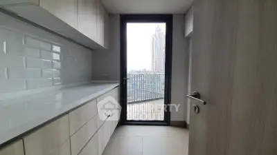 Modern kitchen with sleek cabinetry and balcony view in urban apartment.