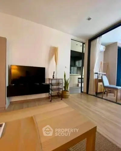 Modern living room with sleek TV setup and open layout leading to dining area.