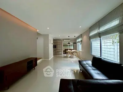 Spacious modern living room with sleek black leather sofa and dining area