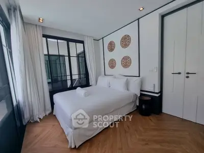 Elegant bedroom with modern decor and large windows in a stylish apartment.