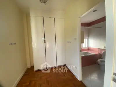 Spacious bedroom with ensuite bathroom featuring elegant parquet flooring and modern fixtures.