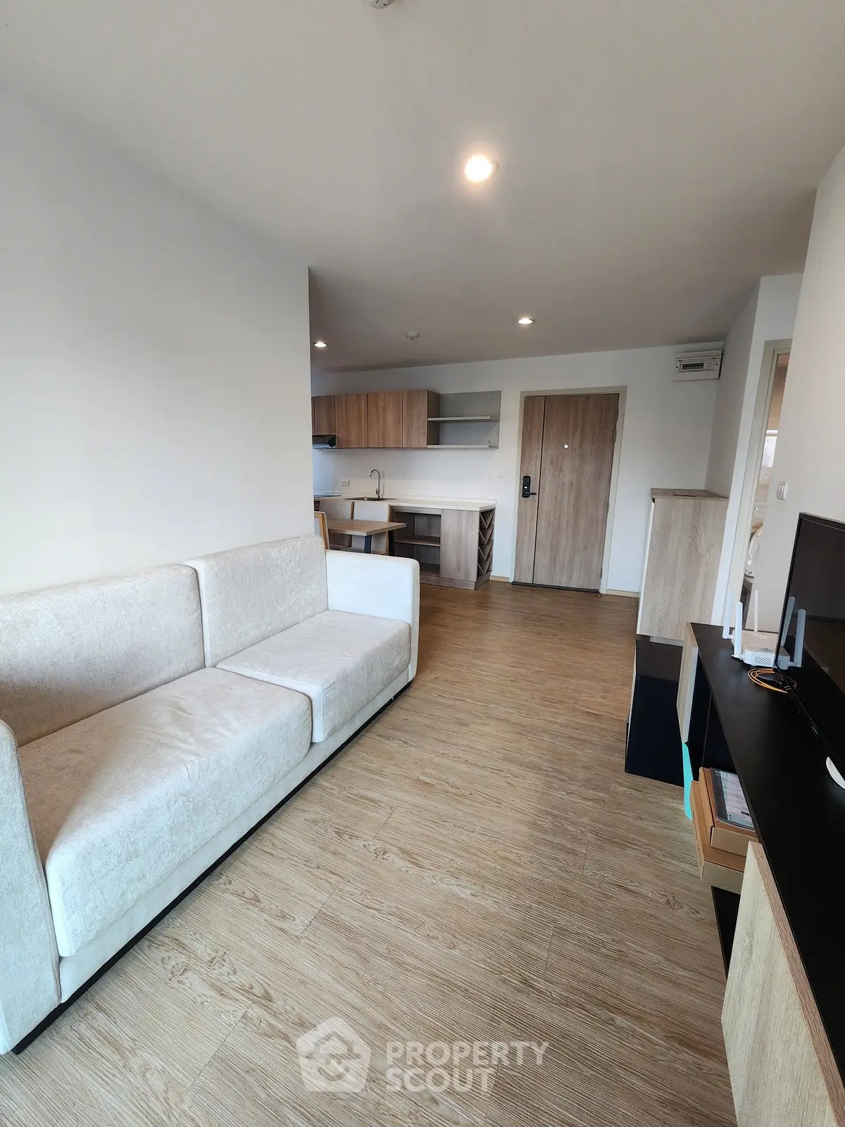 Modern living room with open kitchen layout and stylish wooden flooring.