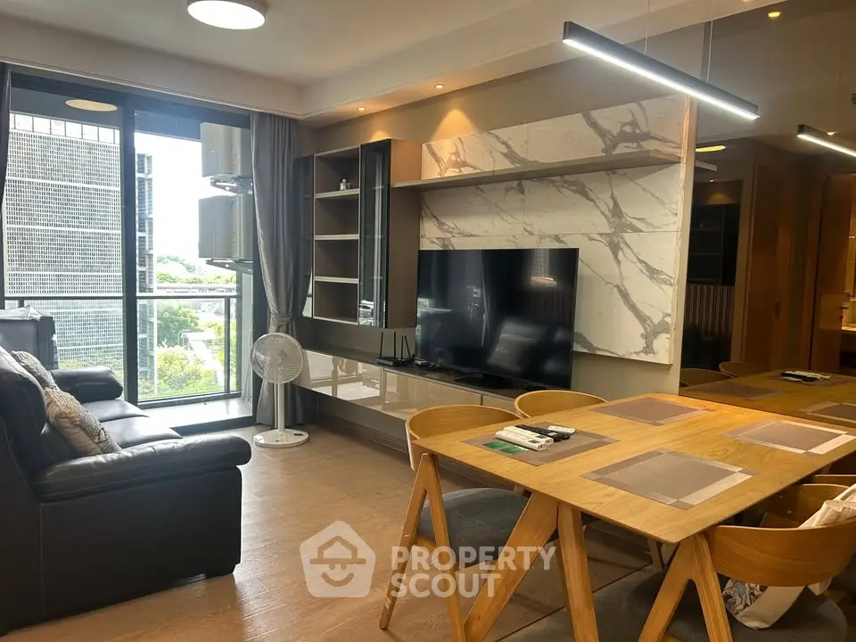 Modern living room with stylish furniture and large TV, featuring a balcony with city view.
