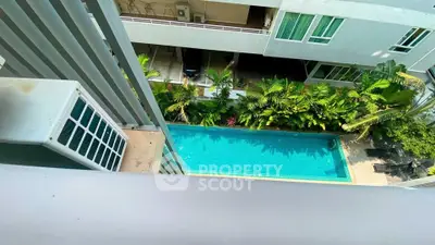 Stunning aerial view of modern apartment pool surrounded by lush greenery
